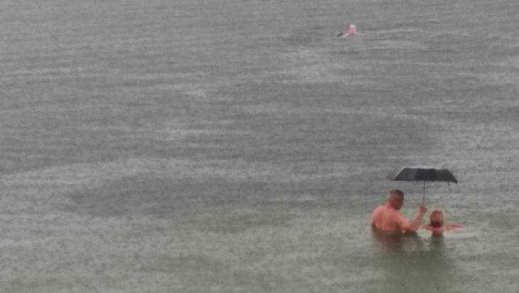 В Брянске сфотографировали купавшуюся с зонтом под дождем компанию